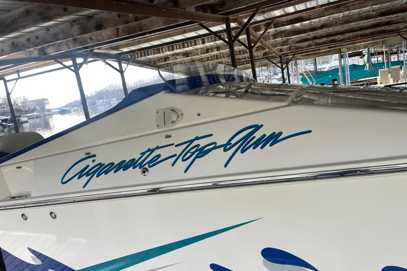 Slide: The Image of 1998 Cigarette 38' Top Gun boat docked under a wooden canopy. - 7