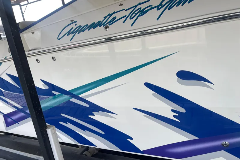 Slide: The Image of 1998 Cigarette 38' Top Gun boat with vibrant blue and teal graphics. - 8