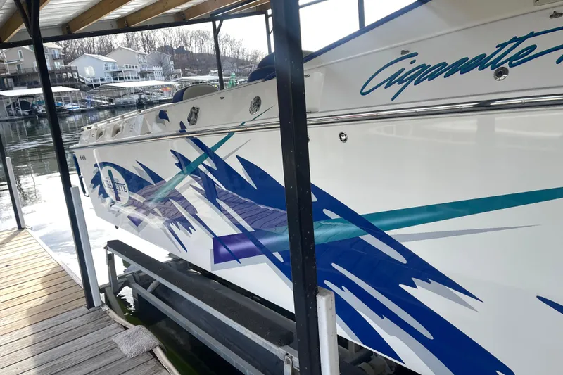 Slide: The Image of 1998 Cigarette 38' Top Gun boat with blue and teal graphics docked at marina. - 9