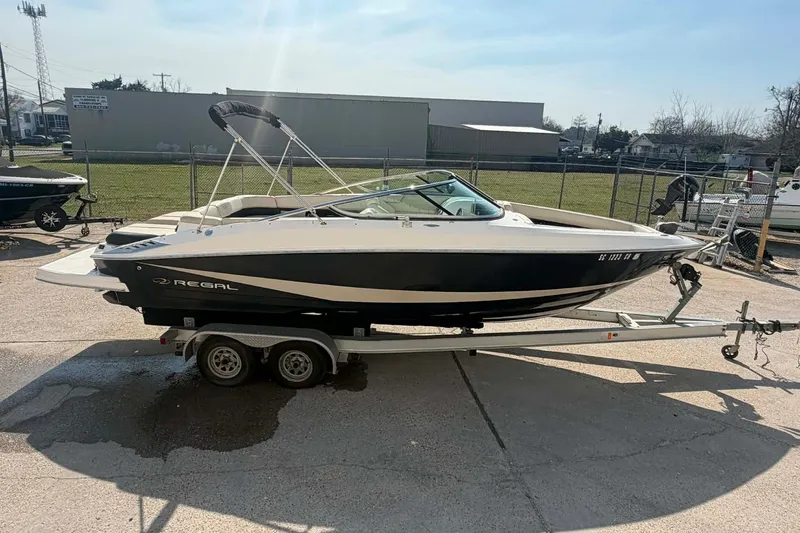 Slide: The Image of 2009 Regal 2500 Bowrider boat on trailer, parked outdoors in a sunny setting. - 2
