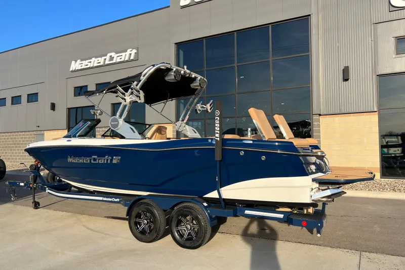 Slide: The Image of 2022 MasterCraft XT25 boat in blue, parked outside dealership, showcasing sleek design. - 3