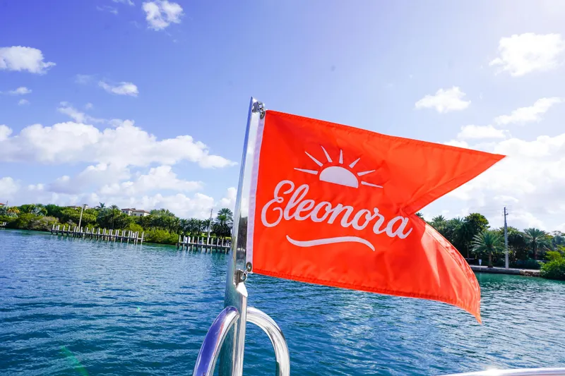 Slide: The Image of Red flag with "Eleonora" on a 2004 Lazzara 80 SL yacht, scenic water backdrop. - 21