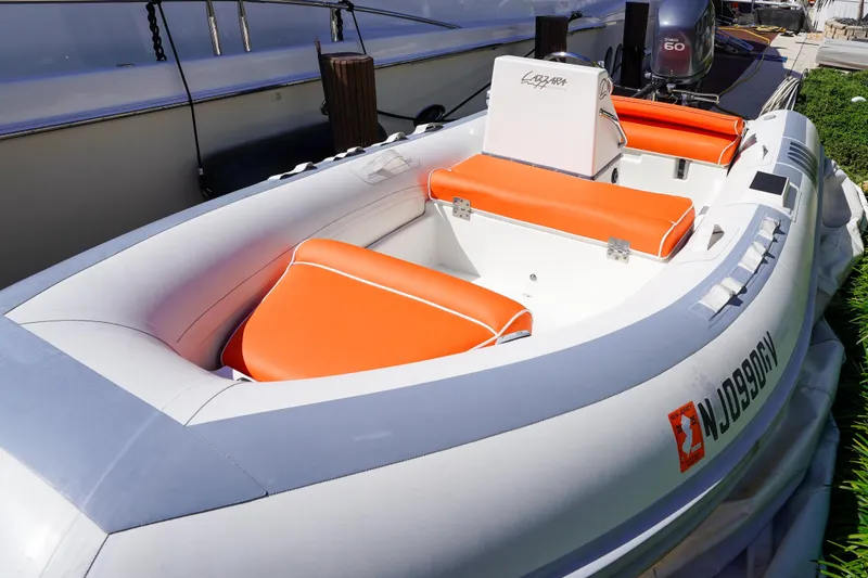 Slide: The Image of Inflatable boat with orange seats, Lazzara 80 SL, 2004 model, docked beside a larger vessel. - 73