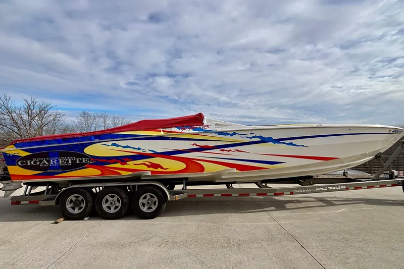 Slide: The Image of 2003 Cigarette 38' Top Gun boat with vibrant graphics on a trailer. - 26