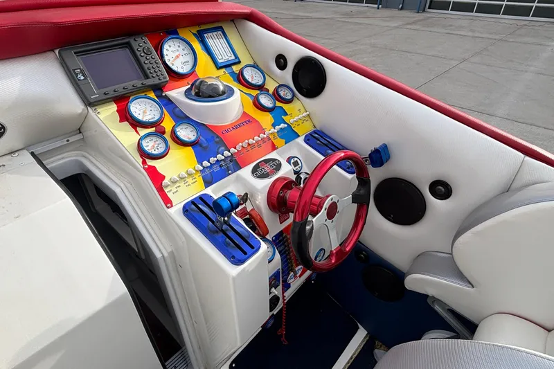 Slide: The Image of 2003 Cigarette 38' Top Gun boat dashboard with colorful gauges and red steering wheel. - 12