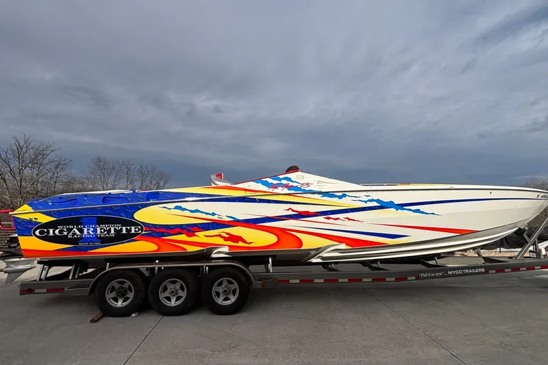 Slide: The Image of 2003 Cigarette 38' Top Gun boat with vibrant graphics on a trailer. - 25