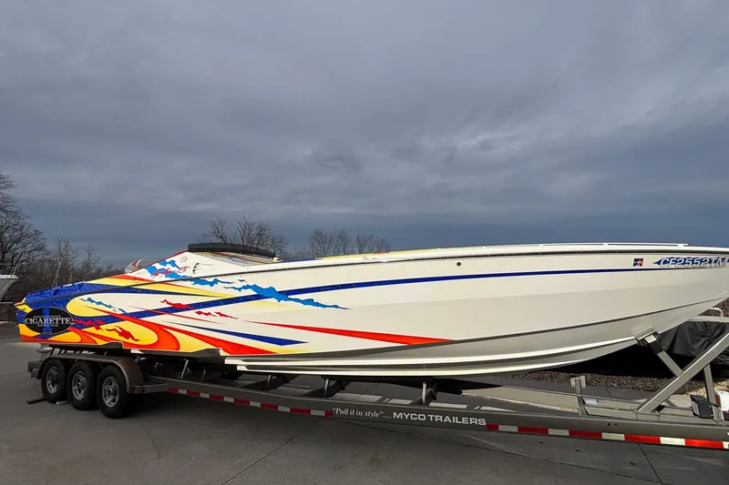 Slide: The Image of 2003 Cigarette 38' Top Gun boat with vibrant graphics on a trailer. - 3