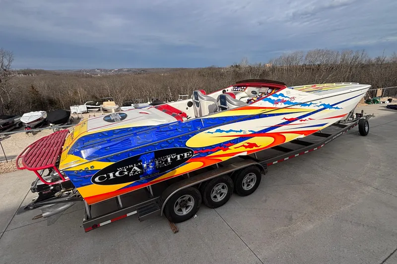 Slide: The Image of 2003 Cigarette 38' Top Gun speedboat with vibrant graphics on a trailer. - 4