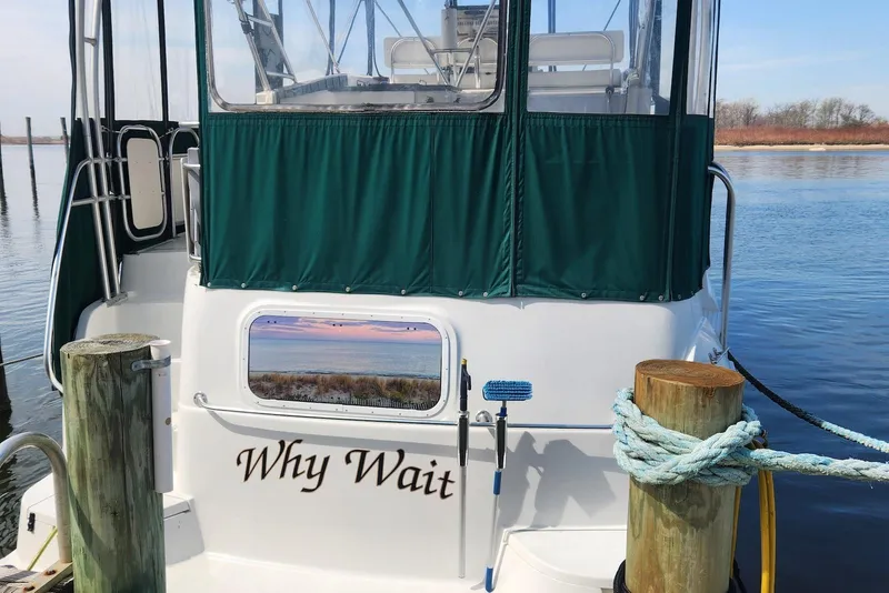 Slide: The Image of 1995 Mainship 37 Motor Yacht docked, featuring green canopy and "Why Wait" name on stern. - 2