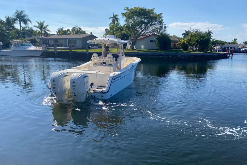 Slide: The Image of 2024 Grady-White Canyon 306 boat cruising on a sunny, palm-lined waterway. - 4