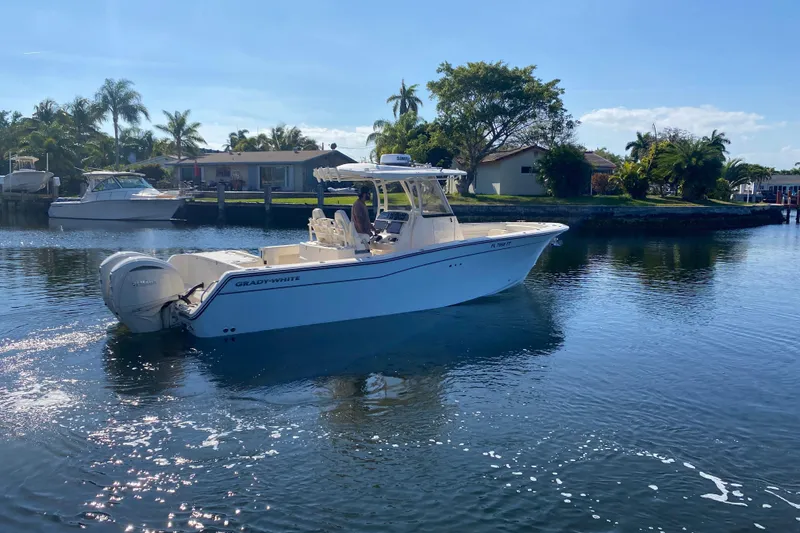 Slide: The Image of 2024 Grady-White Canyon 306 boat cruising on a sunny, palm-lined waterway. - 5
