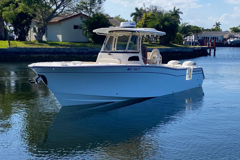 Slide: The Image of 2024 Grady-White Canyon 306 boat cruising on a calm waterway, surrounded by lush greenery. - 7