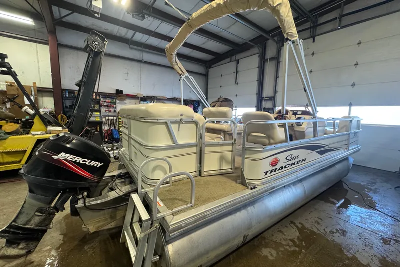 Slide: The Image of 2007 Sun Tracker Party Barge 18 Signature Series pontoon boat in a garage with Mercury outboard. - 2