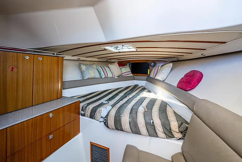 Slide: The Image of 2006 Pursuit 345 Drummond Runner LS cabin interior with cozy bedding and wooden cabinetry. - 23