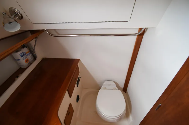 Slide: The Image of 2005 Hinckley Picnic Boat 36 EP bathroom with wooden cabinetry and compact toilet. - 34