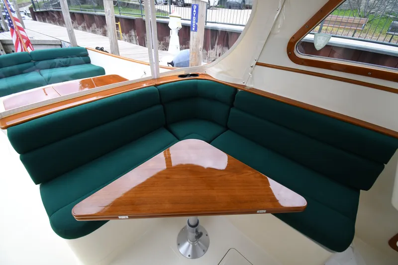 Slide: The Image of Luxurious seating area on a 2005 Hinckley Picnic Boat 36 EP with green cushions and wooden table. - 16