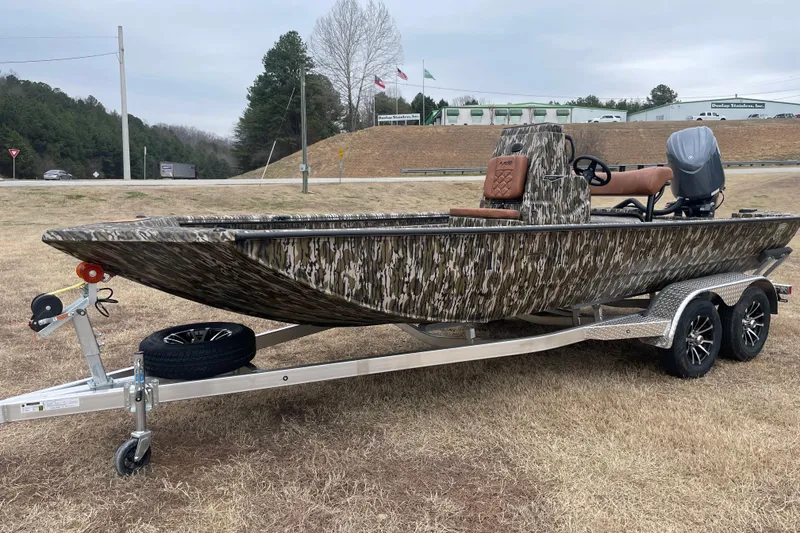 The Image of 2026 Avid 20 Rogue CC boat with camouflage design on a trailer, parked outdoors. - 1