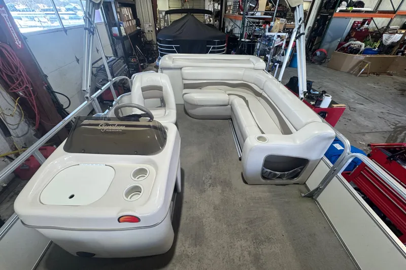 Slide: The Image of 2008 Sun Tracker Party Barge 200 Classic Series interior with seating and helm in a garage. - 11
