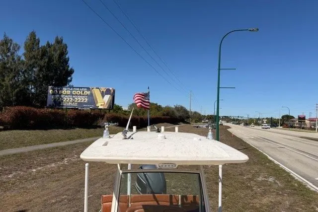 Slide: The Image of 2014 Scout 251 XS boat on trailer beside highway, American flag, billboard in background. - 15