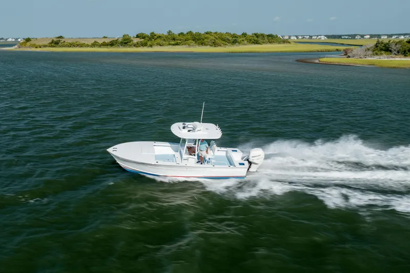 Slide: The Image of 2019 Gamefisherman 26 Cuddy Cabin cruising on open water near a scenic shoreline. - 47