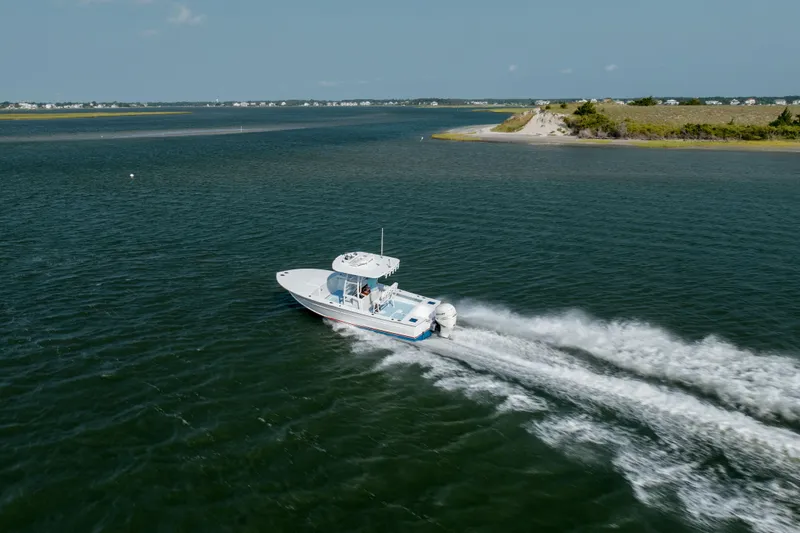 Slide: The Image of 2019 Gamefisherman 26 Cuddy Cabin cruising on open water near a scenic shoreline. - 48