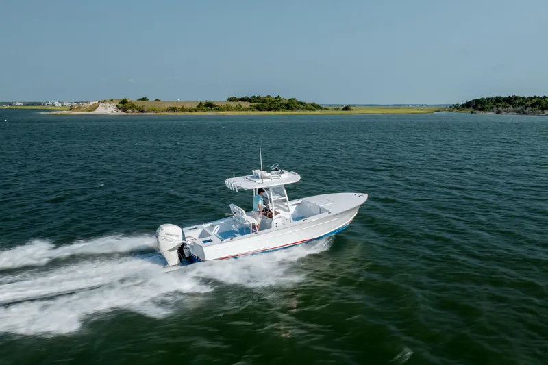 Slide: The Image of 2019 Gamefisherman 26 Cuddy Cabin cruising on open water near a scenic shoreline. - 54