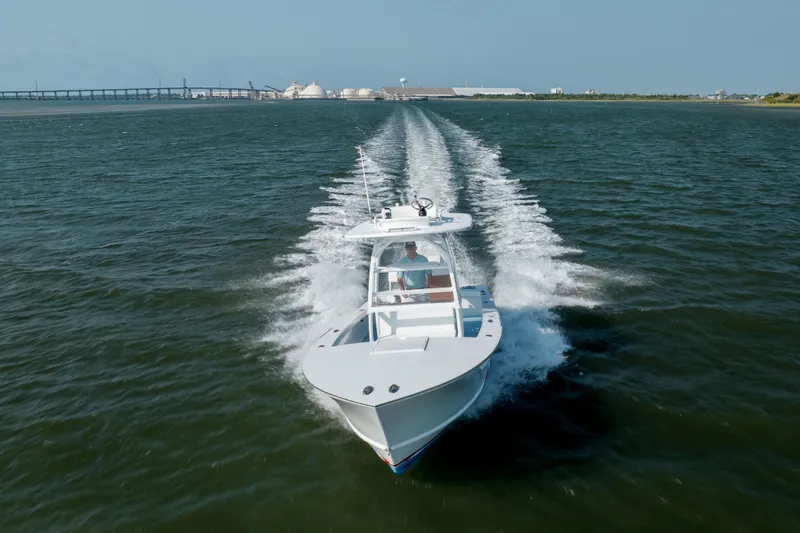 Slide: The Image of 2019 Gamefisherman 26 Cuddy Cabin cruising on open water, creating a wake. - 58