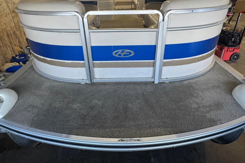 Slide: The Image of 2005 Harris FloteBote 260 Classic pontoon boat with blue and white exterior in a garage. - 3