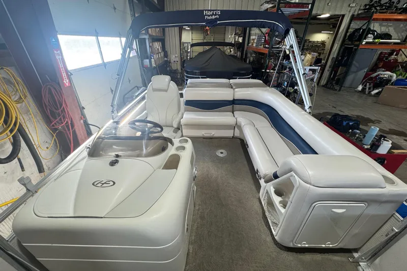 Slide: The Image of 2005 Harris FloteBote 260 Classic pontoon boat interior with seating and helm in a garage. - 9