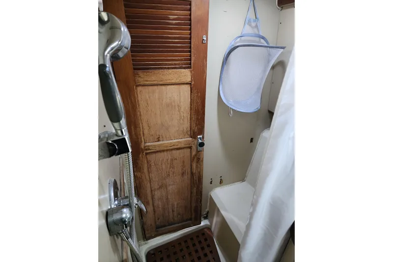 Slide: The Image of 1987 Irwin 44 yacht bathroom with shower, wooden door, and hanging storage. - 34