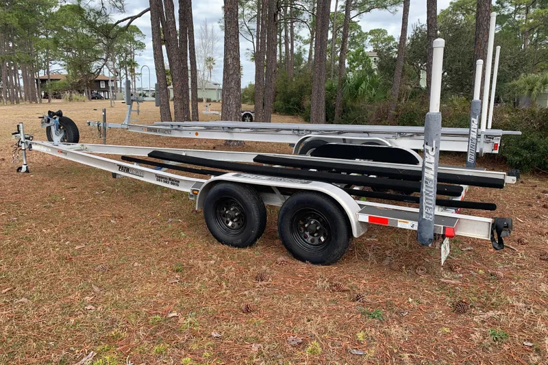 Slide: The Image of 2017 Pathfinder 2400 TRS boat trailer parked on grassy area with trees in background. - 24