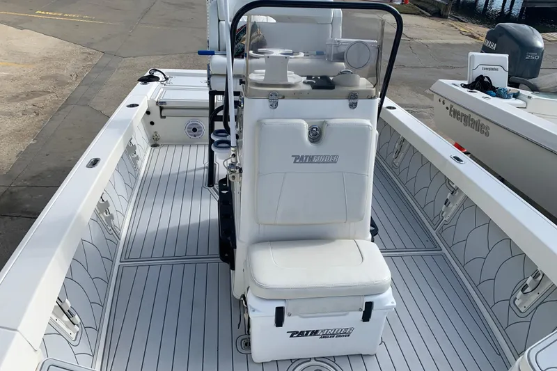 Slide: The Image of 2017 Pathfinder 2400 TRS boat interior with seating and console, docked near water. - 8