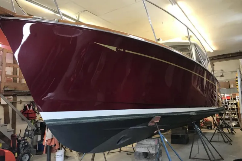Slide: The Image of 2005 Lyman-Morse Monhegan boat in a workshop, featuring a sleek red hull. - 2