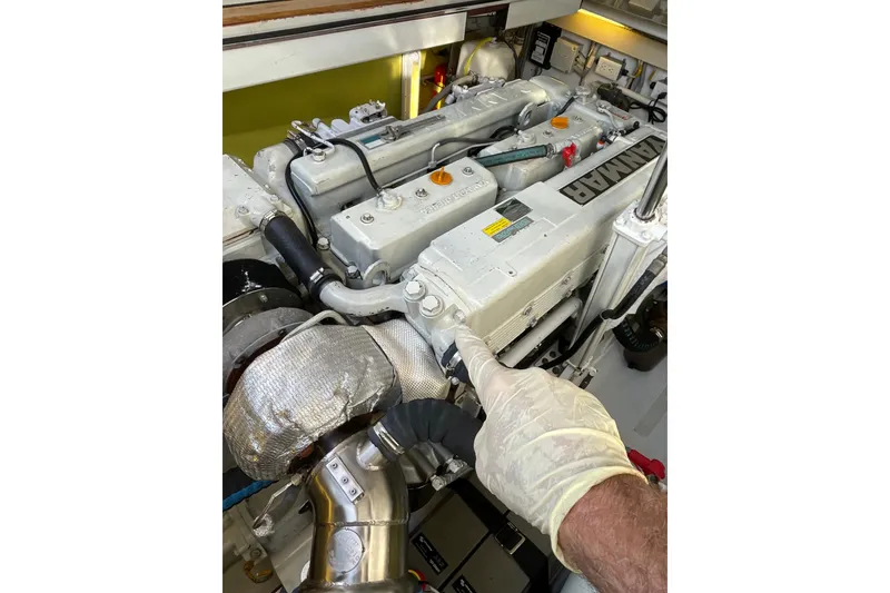 Slide: The Image of Engine of 2005 Lyman-Morse Monhegan boat with Yanmar branding, inspected by gloved hand. - 22