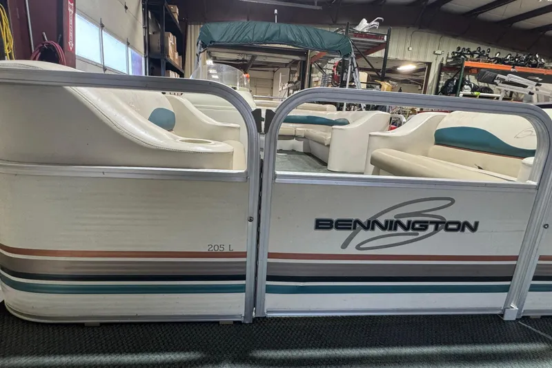 Slide: The Image of 2000 Bennington 205 L pontoon boat with white seating in a warehouse setting. - 4