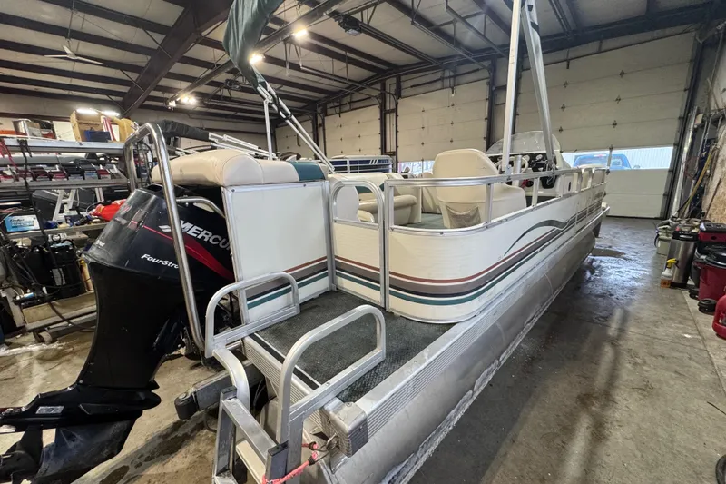 Slide: The Image of 2000 Bennington 205 L pontoon boat in a garage, featuring a Mercury outboard motor. - 5