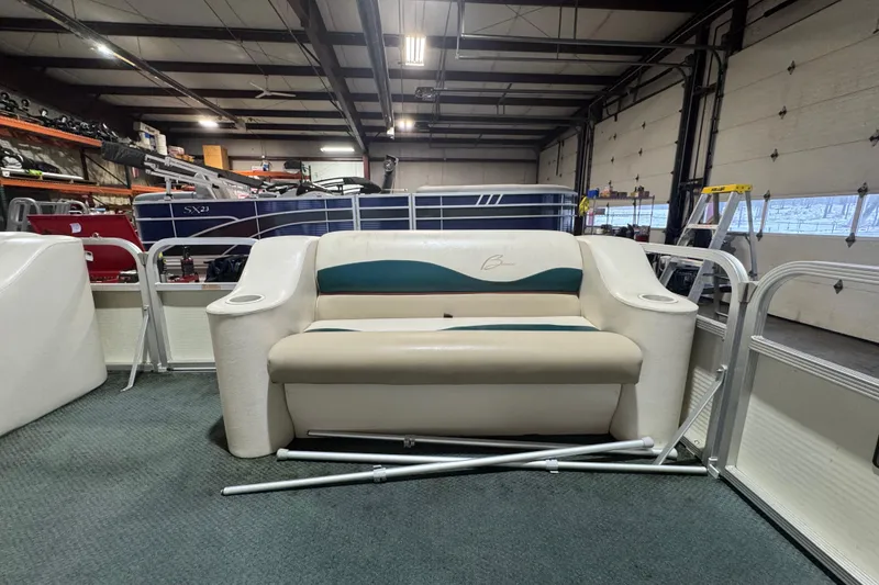 Slide: The Image of 2000 Bennington 205 L boat interior with beige seating in a garage setting. - 6