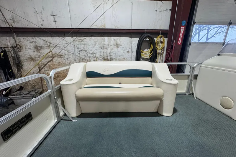 Slide: The Image of 2000 Bennington 205 L boat interior with cushioned seating in a garage setting. - 7