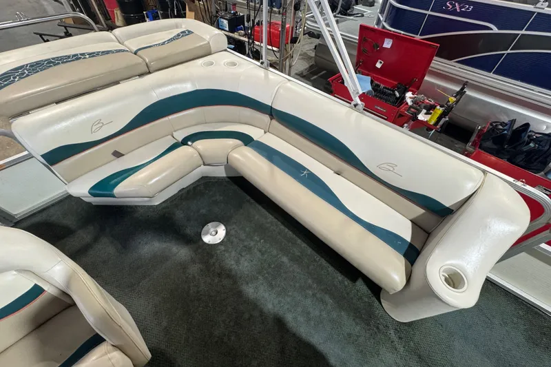 Slide: The Image of Bennington 205 L 2000 boat interior with cream and teal seating in a workshop setting. - 9