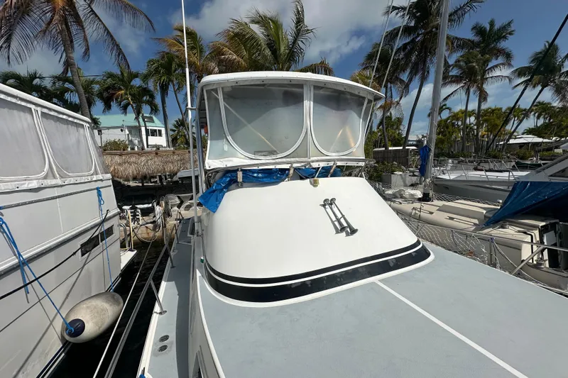 Slide: The Image of 1991 Carver Californian 48 yacht docked, surrounded by palm trees and clear skies. - 12