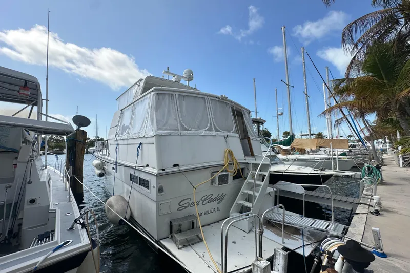 Slide: The Image of 1991 Carver Californian 48 yacht docked at marina, surrounded by other boats and palm trees. - 14