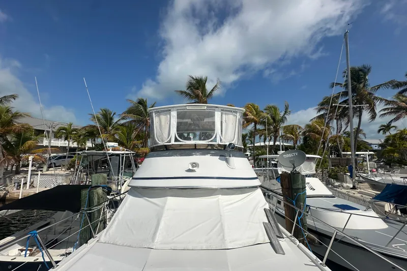 Slide: The Image of 1991 Carver Californian 48 yacht docked, surrounded by palm trees under a clear blue sky. - 4