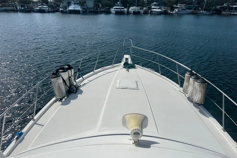 Slide: The Image of 1991 Carver Californian 48 yacht bow view, docked in a serene marina. - 5