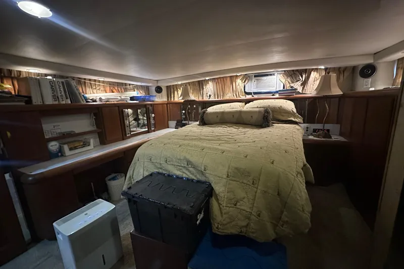 Slide: The Image of 1991 Carver Californian 48 yacht bedroom with cozy bed, wooden shelves, and ambient lighting. - 58