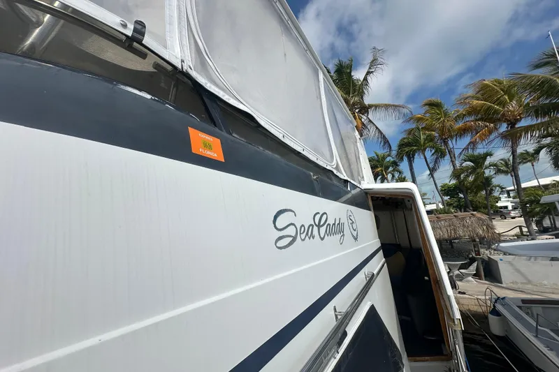 Slide: The Image of 1991 Carver Californian 48 yacht docked, featuring "Sea Caddy" name, palm trees in background. - 7