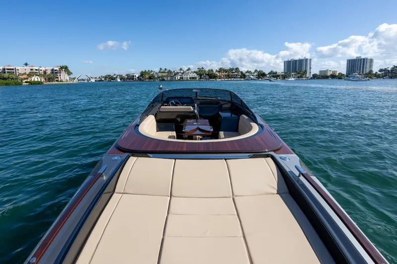 Slide: The Image of 2025 Riva 33' Aquariva Special luxury boat on serene water with cityscape background. - 21