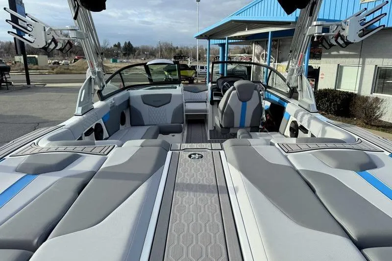 Slide: The Image of 2023 MasterCraft XT22 boat interior with gray and blue seating, docked outdoors. - 11