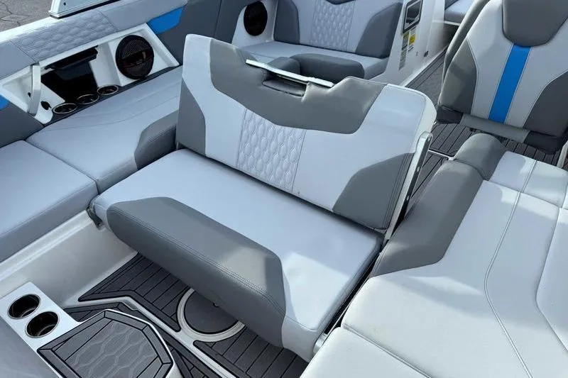 Slide: The Image of 2023 MasterCraft XT22 interior with gray and blue seating, cup holders, and speakers. - 14