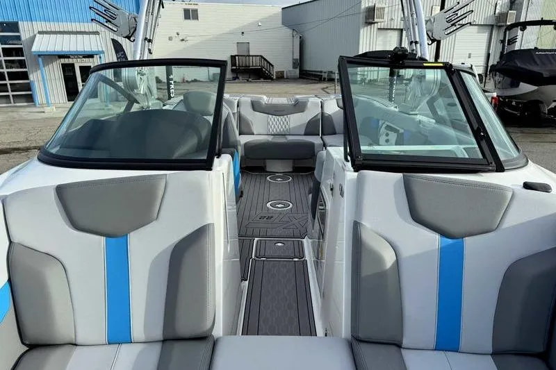 Slide: The Image of 2023 MasterCraft XT22 boat interior with gray and blue seating, open windshield, and modern design. - 15