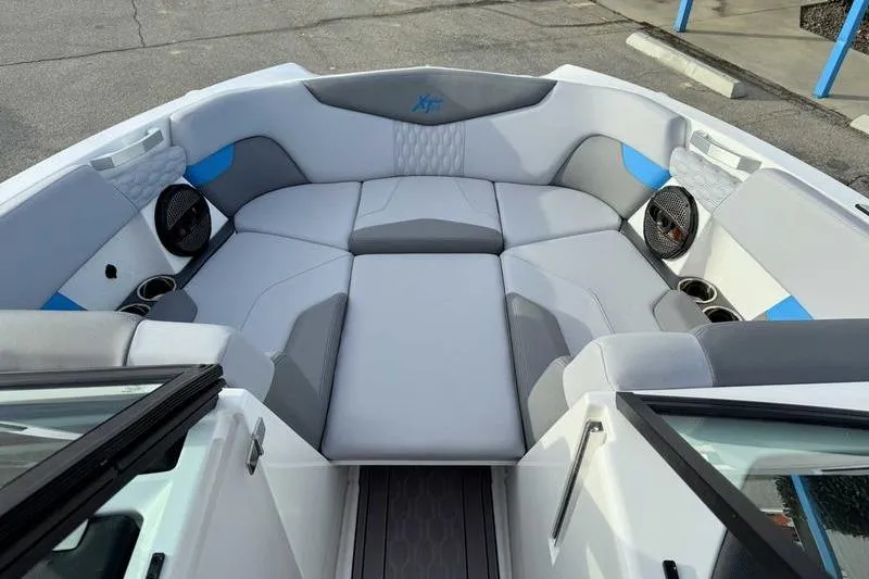 Slide: The Image of 2023 MasterCraft XT22 boat interior with gray and blue seating, cup holders, and speakers. - 16
